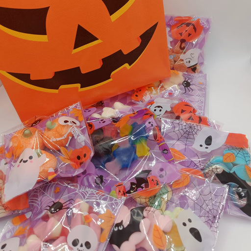 Halloween-themed goodie bags with a pumpkin design and candy packages on a white background