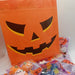 Halloween-themed goodie bags with a jack-o'-lantern design on an orange bag.